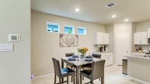 A modern kitchen with white cabinets, a dining table set for four, and a small window with a view. - Family-Friendly Fort Worth Home: Private Yard (Fort Worth)