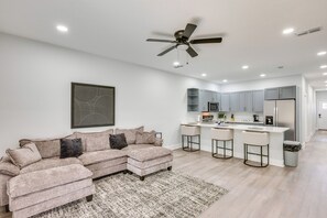 A modern kitchen with white cabinets, a central island with bar stools, and a ceiling fan. - 3 Mi to Dtwn & EverBank Stadium! Family Townhome (Jacksonville)