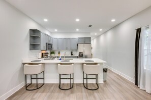A modern kitchen with a central island, bar stools, and a built-in oven. - 3 Mi to Dtwn & EverBank Stadium! Family Townhome (Jacksonville)