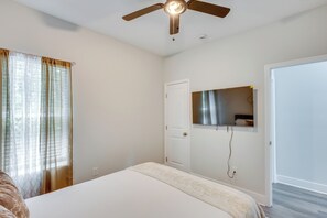 Ein Schlafzimmer mit einem Bett, einem Deckenventilator, einer Tür und einem Spiegel an der Wand.