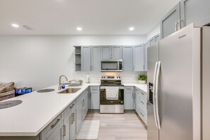 A modern kitchen with grey cabinets, stainless steel appliances, and a large island with a sink. - 3 Mi to Dtwn & EverBank Stadium! Family Townhome (Jacksonville)