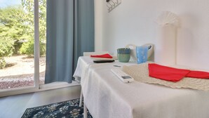 A room with a bed, a table with a remote control, a red cloth, and a view of greenery outside. - Soaking Tub, Fire Pit! Hemet Studio Suite (Hemet)