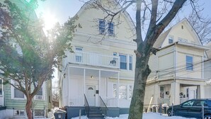Ein zweigeschossiges Haus mit Veranda, einer sichtbaren Treppe und einem Auto auf der Auffahrt.