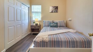 Um quarto com uma cama, uma mesa de cabeceira, uma janela e uma porta.