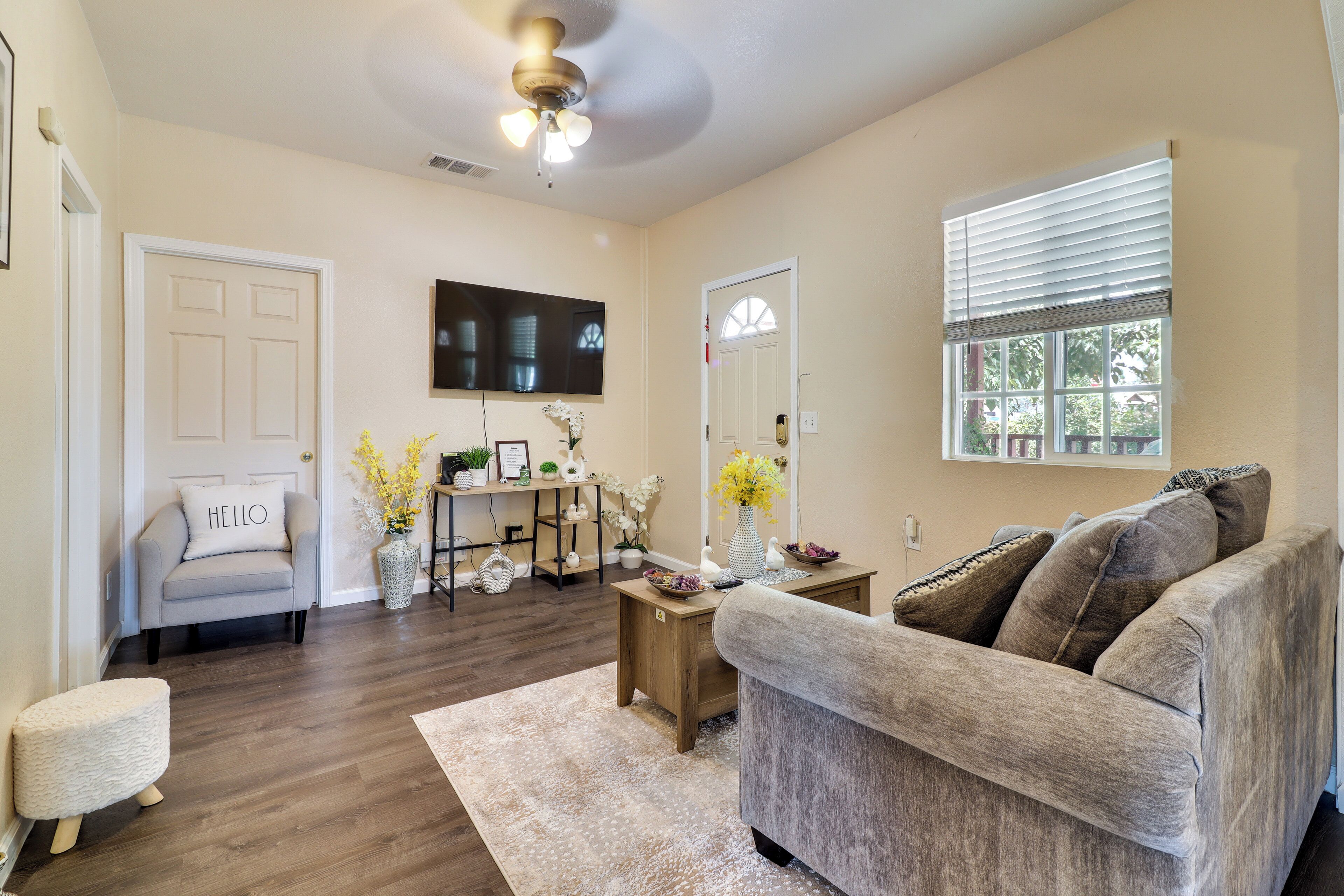 A living room with a sofa, a coffee table, a TV, and a window with blinds.