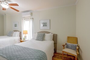 Ein Hotelzimmer mit zwei Betten, einem Sessel, einem Deckenventilator und Bildern an den Wänden.