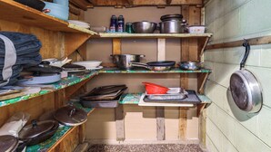 A compact kitchen with wooden shelves, various cooking utensils, and pots. - 8 Mi to Dtwn Detroit! Apt w/ Shared Yard (Dearborn)