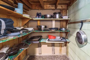 Eine kleine Küche mit Holzböden, Kochgeschirr und Töpfen.