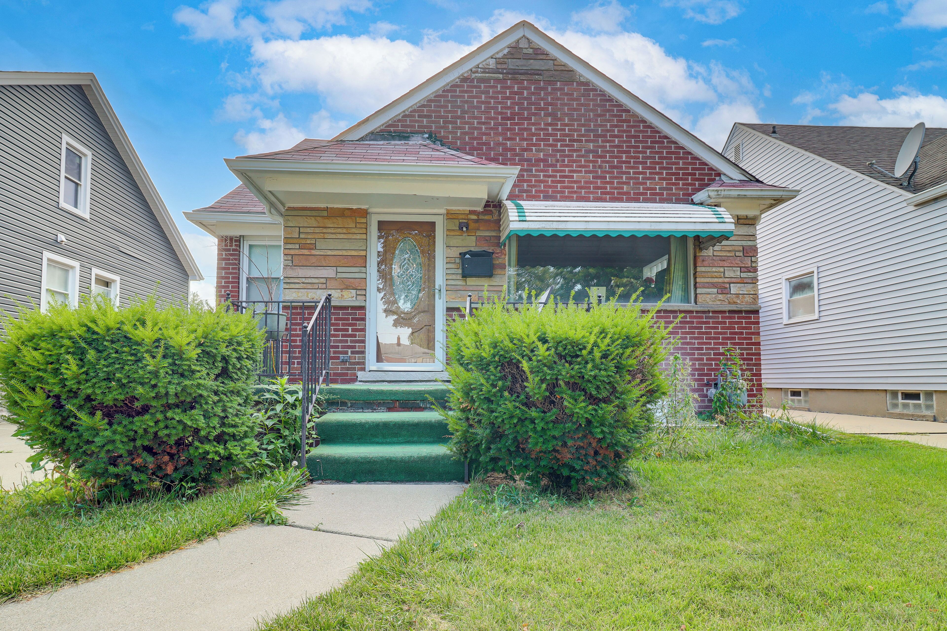 A residential house with a brick facade, a front porch, and a satellite dish.