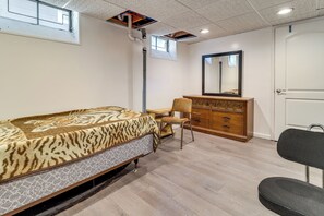 Ein Schlafzimmer mit Bett, Kommode, Stuhl und Spiegel.