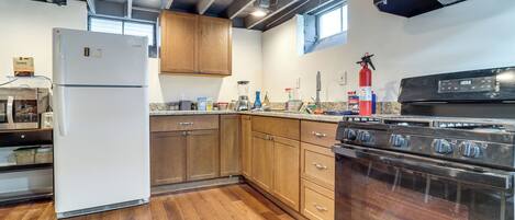 A kitchen with wooden cabinets, a white refrigerator, a stove, and a window.