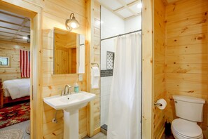 Ein Holzinnenraum mit Bad, inklusive Waschbecken, Toilette und Duschvorhang.