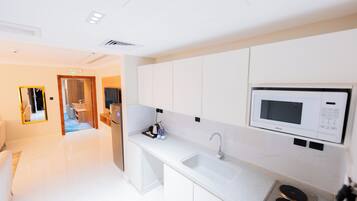 Una cocina moderna con armarios blancos, un microondas integrado y un lavamanos de acero inoxidable.