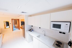 A modern kitchen with white cabinets, a built-in microwave, and a stainless steel sink.