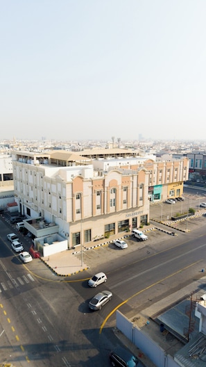 Un edificio de varios pisos con una planta baja comercial, estacionamiento y una vista despejada del paisaje urbano circundante.