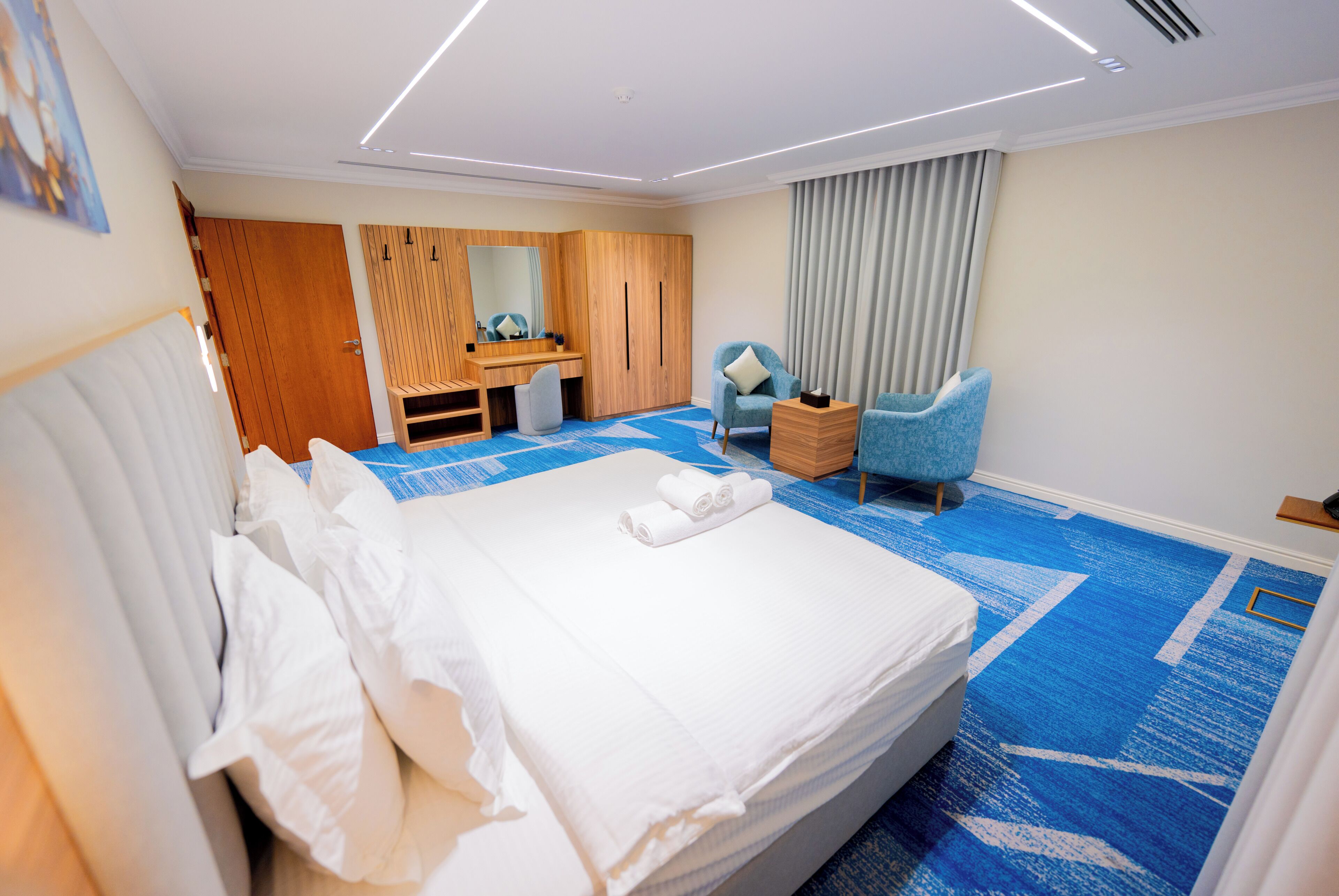 A hotel room with a large bed, a desk, a chair, and a bathroom.