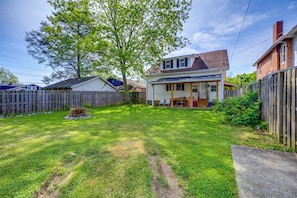A residential backyard with a wooden fence, a lawn, and a house with a porch. - Bristol House & Studio Near State Street (Bristol)