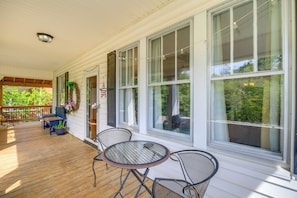 A covered porch with a table and chairs, large windows, and a view of greenery. - Bristol House & Studio Near State Street (Bristol)