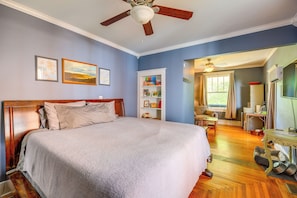 A bedroom with a large bed, a ceiling fan, a wooden headboard, a built-in bookshelf, and a window with curtains. - Bristol House & Studio Near State Street (Bristol)