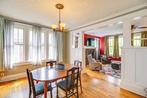 A dining area with a wooden table and chairs, a fireplace, and a television in a living room with red walls. - Bristol House & Studio Near State Street (Bristol)
