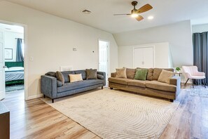 A spacious living room with two sofas, a ceiling fan, and a large rug. - 3 Kitchens: Spacious & Convenient Newark Home! (Newark)
