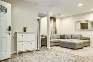 Ein modernes Wohnzimmer mit einem weißen Schrank, einer Stehlampe, einem grauen Sofa und einem gemusterten Teppich.