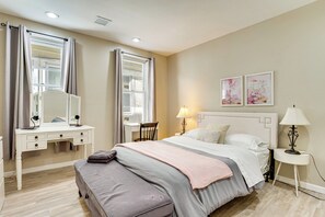A bedroom with a bed, a desk, a chair, a bedside table with a lamp, and two framed artworks on the wall. - 3 Kitchens: Spacious & Convenient Newark Home! (Newark)