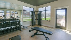 Une salle de sport équipée de machines d’exercice, d’un banc et d’haltères.
