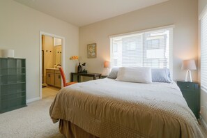 A bedroom with a bed, bedside tables, a dresser, a window with blinds, and a door leading to a bathroom. - Extended Stay In Fort Collins! Townhome w/ Gym (Fort Collins)