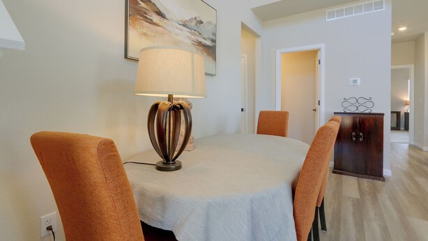 Un coin repas comprenant une table, des chaises, une lampe et un tableau accroché au mur.