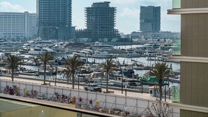 Un port de plaisance où sont amarrés de nombreux bateaux, entouré d’immeubles de grande hauteur et de palmiers.