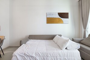 Un dormitorio moderno con cama, sofá y una obra de arte abstracta en la pared.