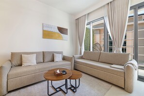 Un salon moderne avec deux canapés, une table basse et un tableau accroché au mur.