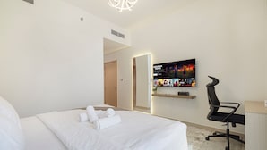 Une chambre d’hôtel comprenant un lit, un bureau, une chaise, un téléviseur fixé au mur et une porte donnant sur une autre pièce.