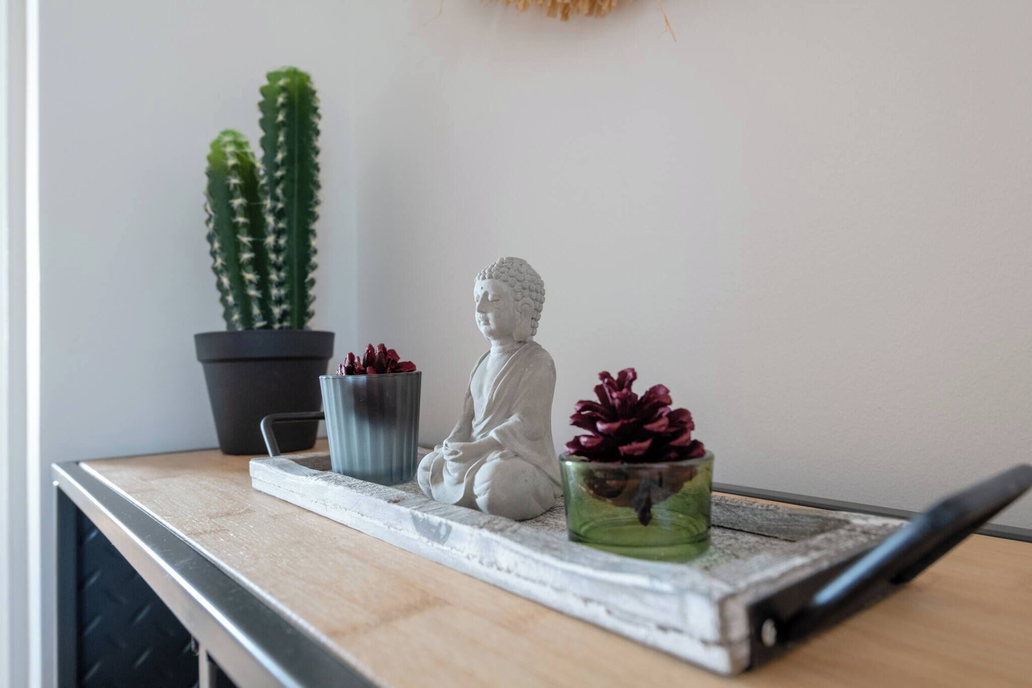 A statue of a seated figure on a tray with two potted plants.