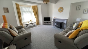 A living room with two sofas, a television, a fireplace, and a window with curtains. - Loch linnhe view house, Fort William (Caol)