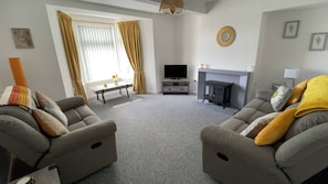 A living room with two sofas, a television, a fireplace, and a window with curtains. - Loch linnhe view house, Fort William (Caol)