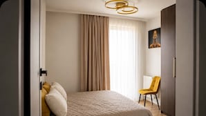 A bedroom with a bed, a chair, a painting, and a door.