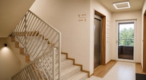 A modern interior with a staircase, an elevator, and a door leading to a balcony.