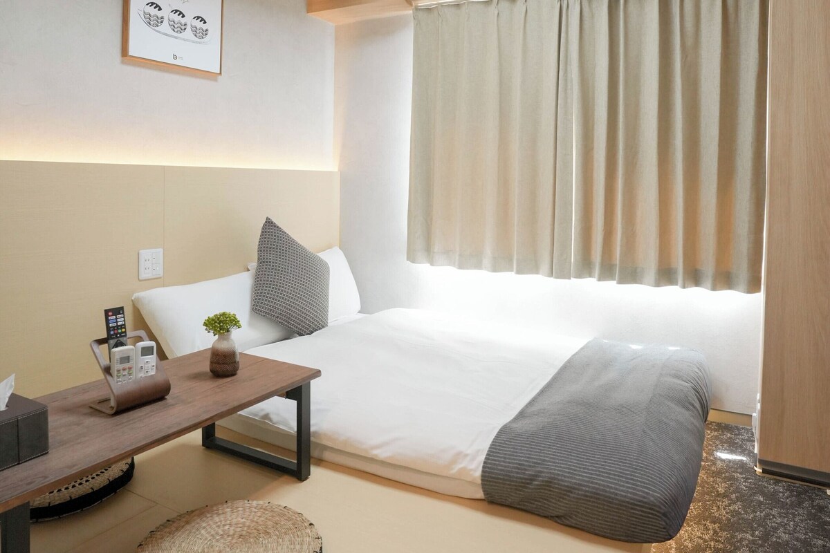 Ein modernes Hotelzimmer mit Bett, Nachttisch, Lampe, Klimaanlage und Blick ins Freie.