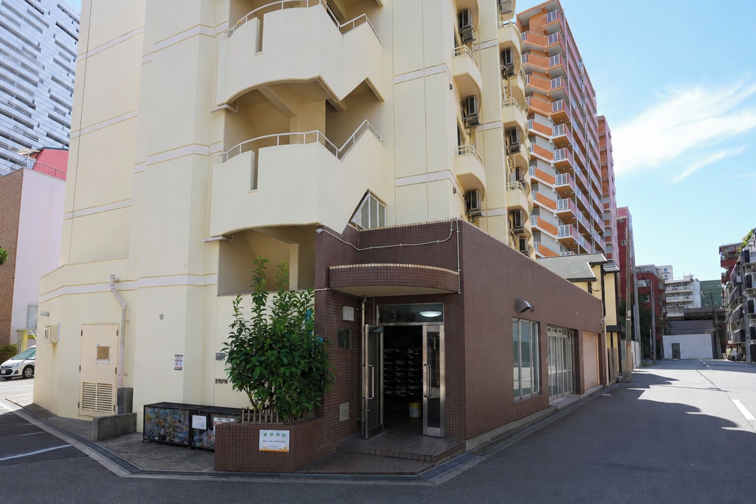 A multi-story building with a ground-level entrance, a small garden area, and a visible balcony.