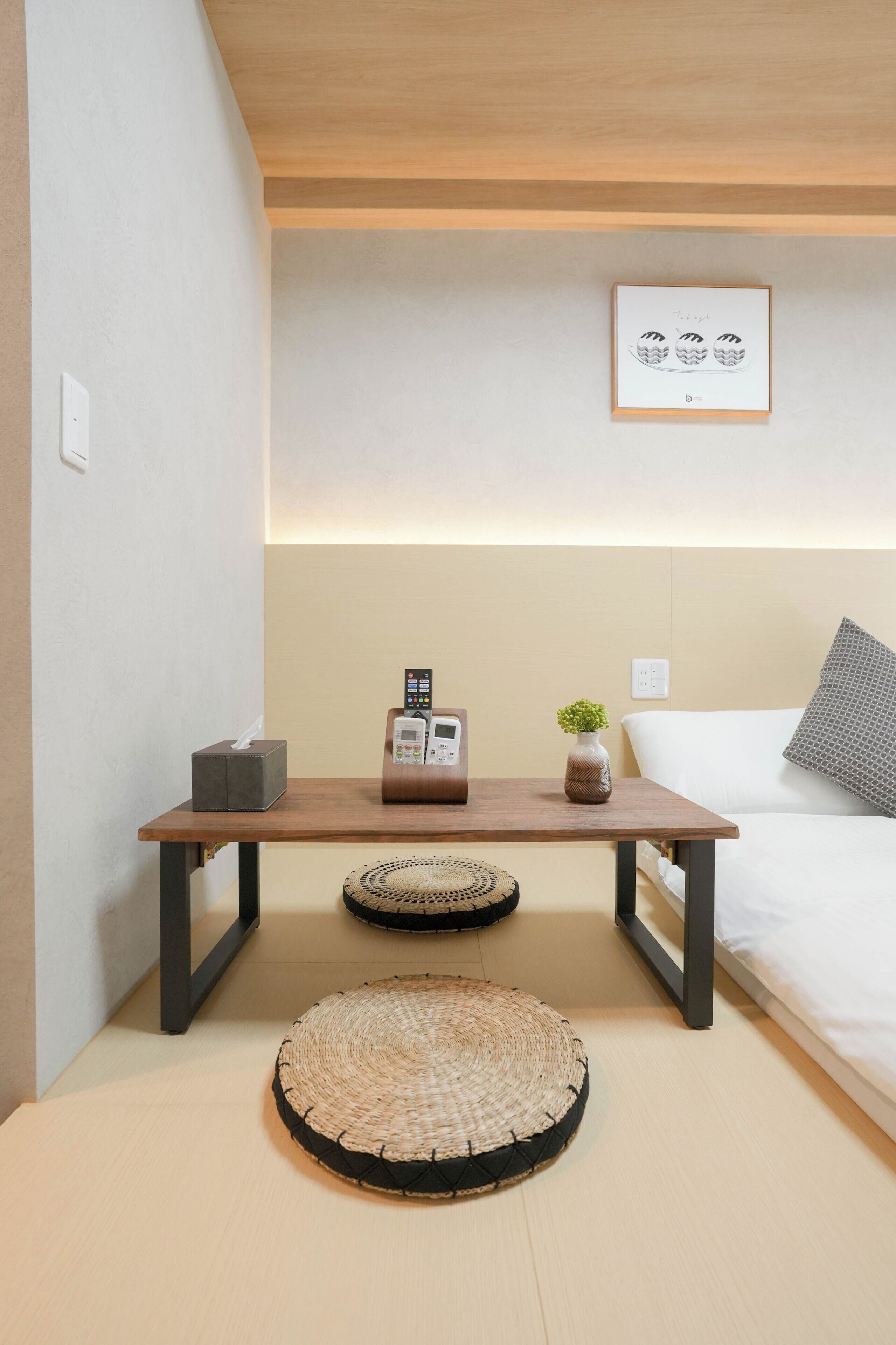 Un dormitorio ordenado con una cama, una mesita de noche y un cuadro en la pared.