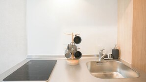 A modern kitchen with a built-in induction cooktop, a stainless steel sink, and a wooden utensil rack. - b&Tsutenkaku 4 (Naniwa Ward,Osaka)