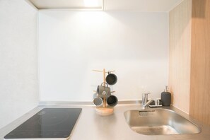 Eine moderne Küche mit integriertem Induktionskochfeld, einer Edelstahl-Spüle und einem Holz-Gewürzregal.