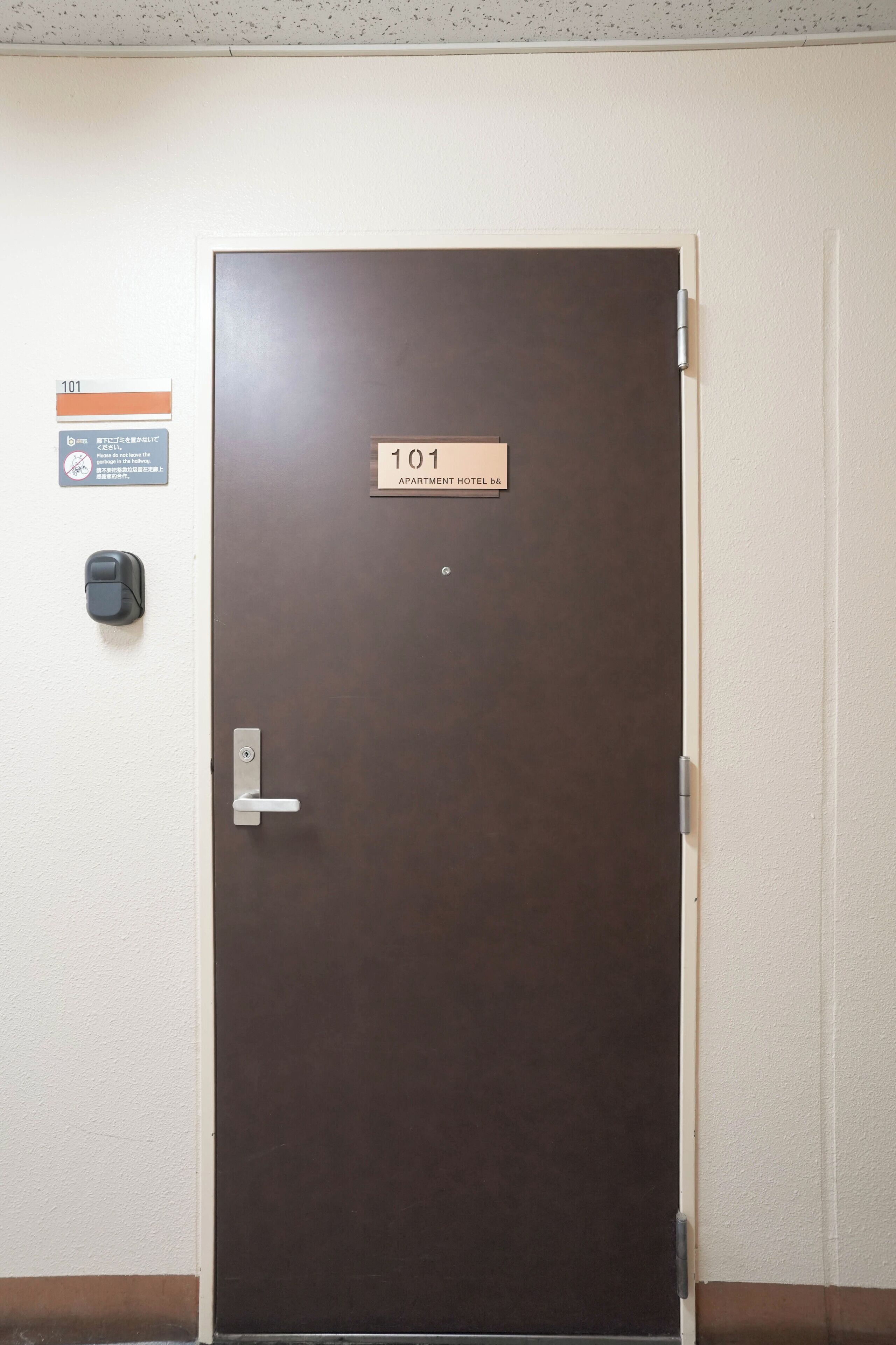 A hotel room door with a sign indicating room number 101 and a note about not leaving the garbage in the hallway.
