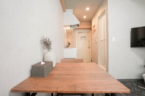 Un pasillo con una mesa de madera, un florero con ramas y una caja de pañuelos.