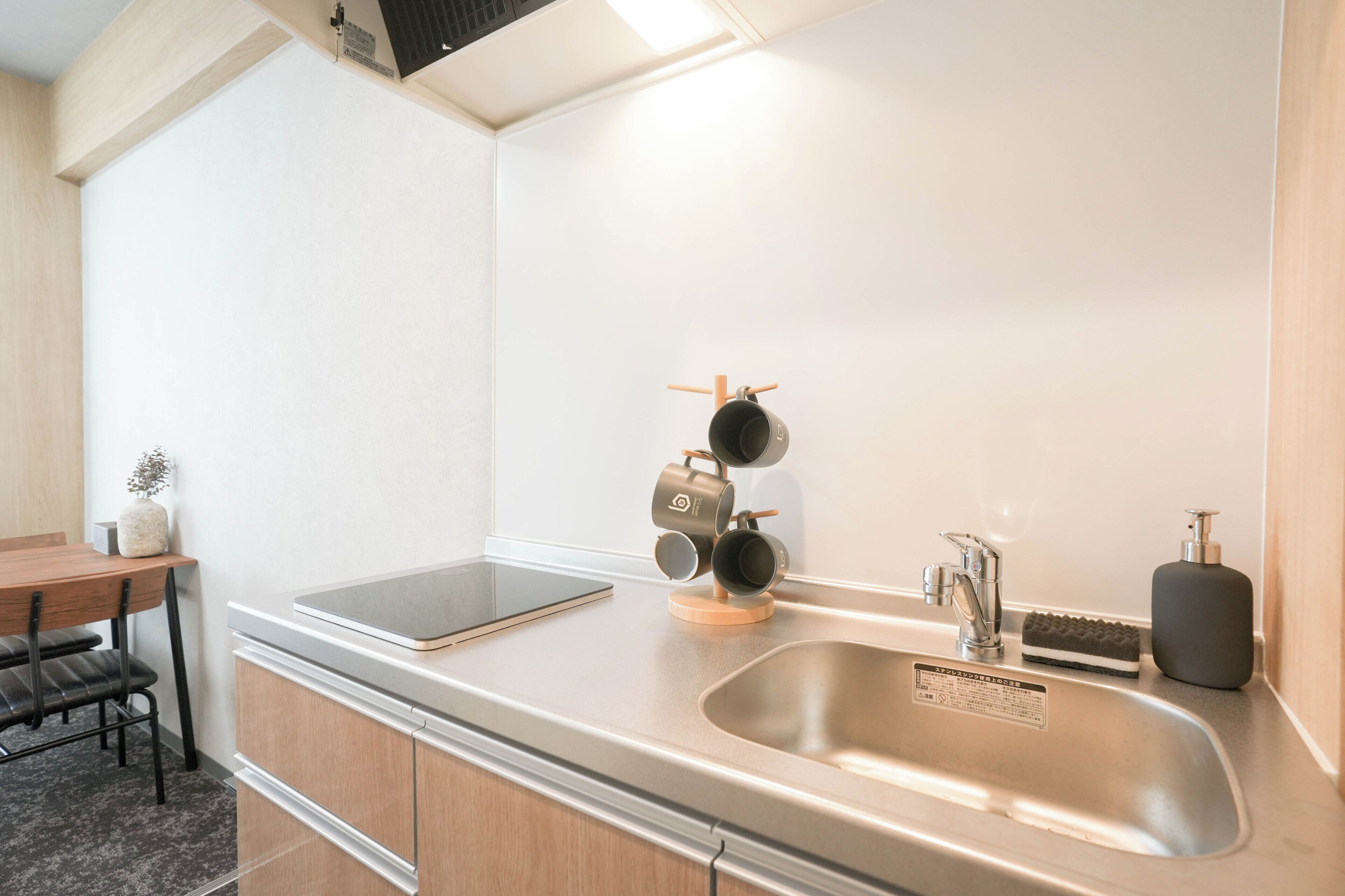 Una cocina moderna con un lavamanos de acero inoxidable, una mesa de madera y un colgador para ollas.