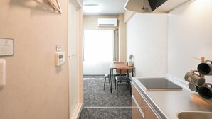A compact kitchen with a dining area, a built-in air conditioner, and a small table with chairs. - b&Tsutenkaku 4 (Naniwa Ward,Osaka)