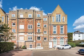 A multi-story residential building with a brick facade, multiple windows, and a gated entrance. - Chic 1BDR Flat in De Beauvoir Town (London)