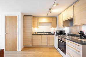 Eine moderne Küche mit Holzausstattung, einem Gasherd und einem eingebauten Backofen.
